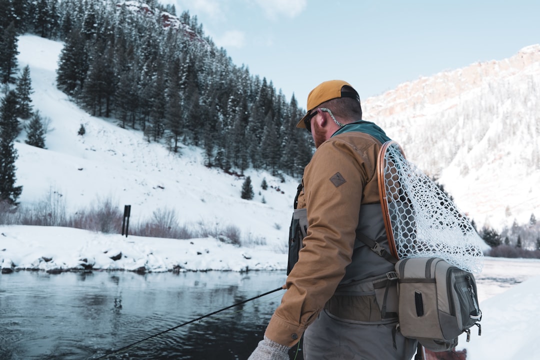 Chasseur équipé au bord d'une rivière en hiver